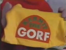 A still from an episode of Sesame Street with a puppet holding up a "Kermit the Gorf" shirt.