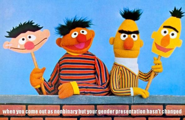 Ernie and Bert at a low brick wall. Ernie is smiling and holds a mask of his own face crying. Bert is frowning and holds a mask of his own face smiling. Caption: “when you come out as nonbinary but your gender presentation hasn’t changed”